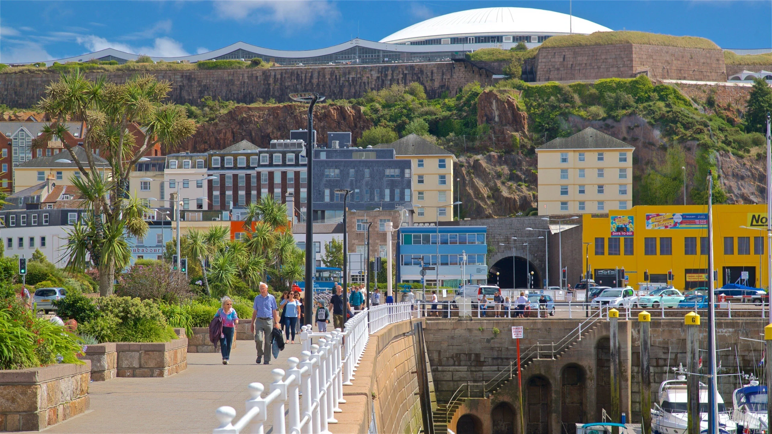The image shows the historic Port of St. Andrews in St. Andrews, Scotland, with a panoramic view of the cityscape, including the iconic white dome and the Port of St. Andrews. The city is bustling with activity, and the clear blue sky suggests a sunny day. The image captures the city's charm and history, with the Port of St. Andrews as a central focus.